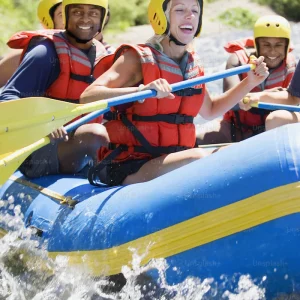 man and woman smiling while paddling on a whitewater rafting tour