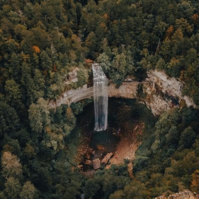 Aerial shot of large waterfall over valley in the middle of the woods