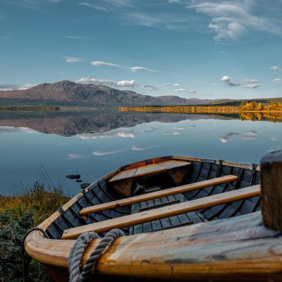 Old wooden boat on a lake shore at sunset for adventure