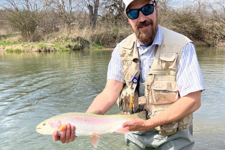 Virginia fly fishing guide in vest and waders holding a big fish for a picture while standing in the Shenandoah River near Charlottesville VA.