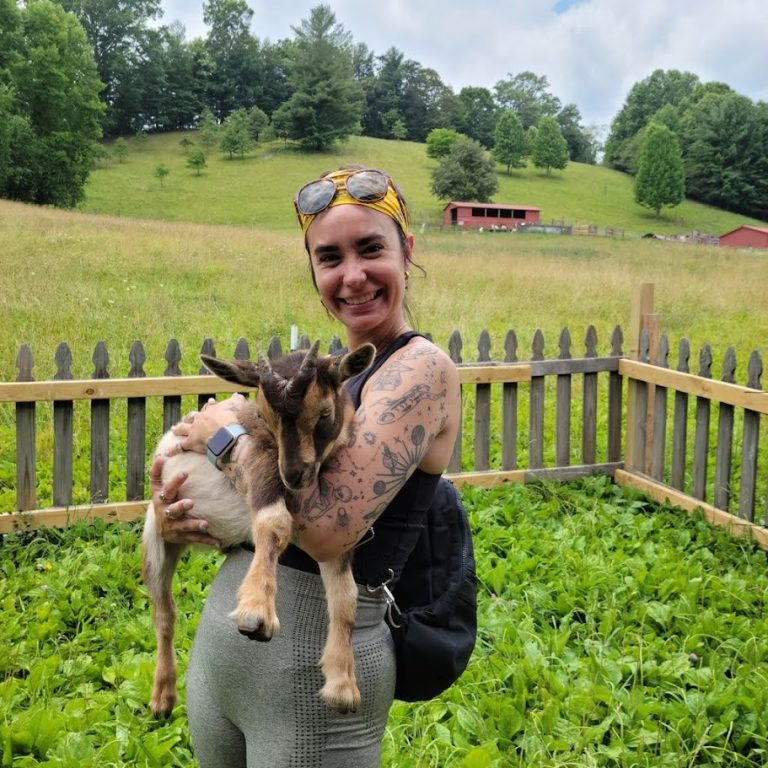 women holding goat during baby goat yoga