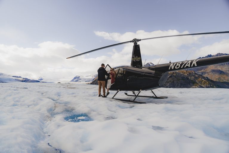 couple getting out of a helicopter about to elope in alaska