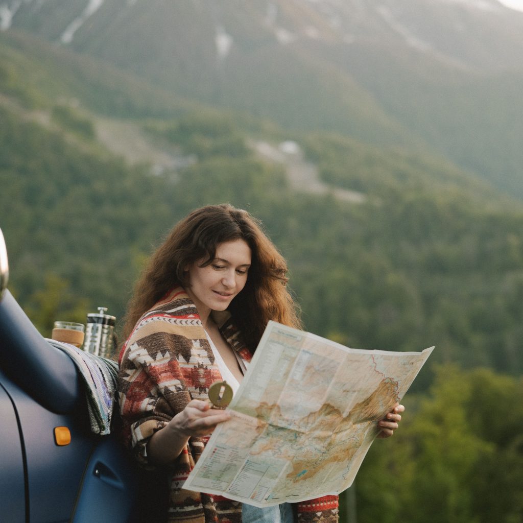 women standing outside a car looking at a compass and map