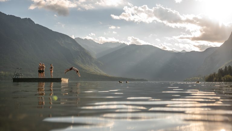 group of friends swimming in the middle of a lake with mountains in background
