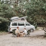 couple sipping coffee by campervan on vacation