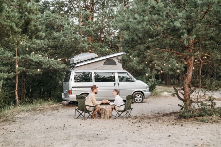 couple sipping coffee by campervan on vacation
