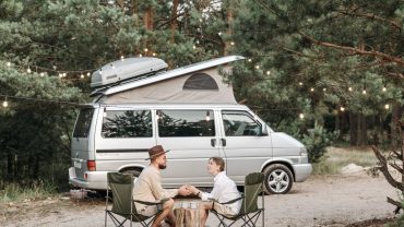 couple sipping coffee by campervan on vacation